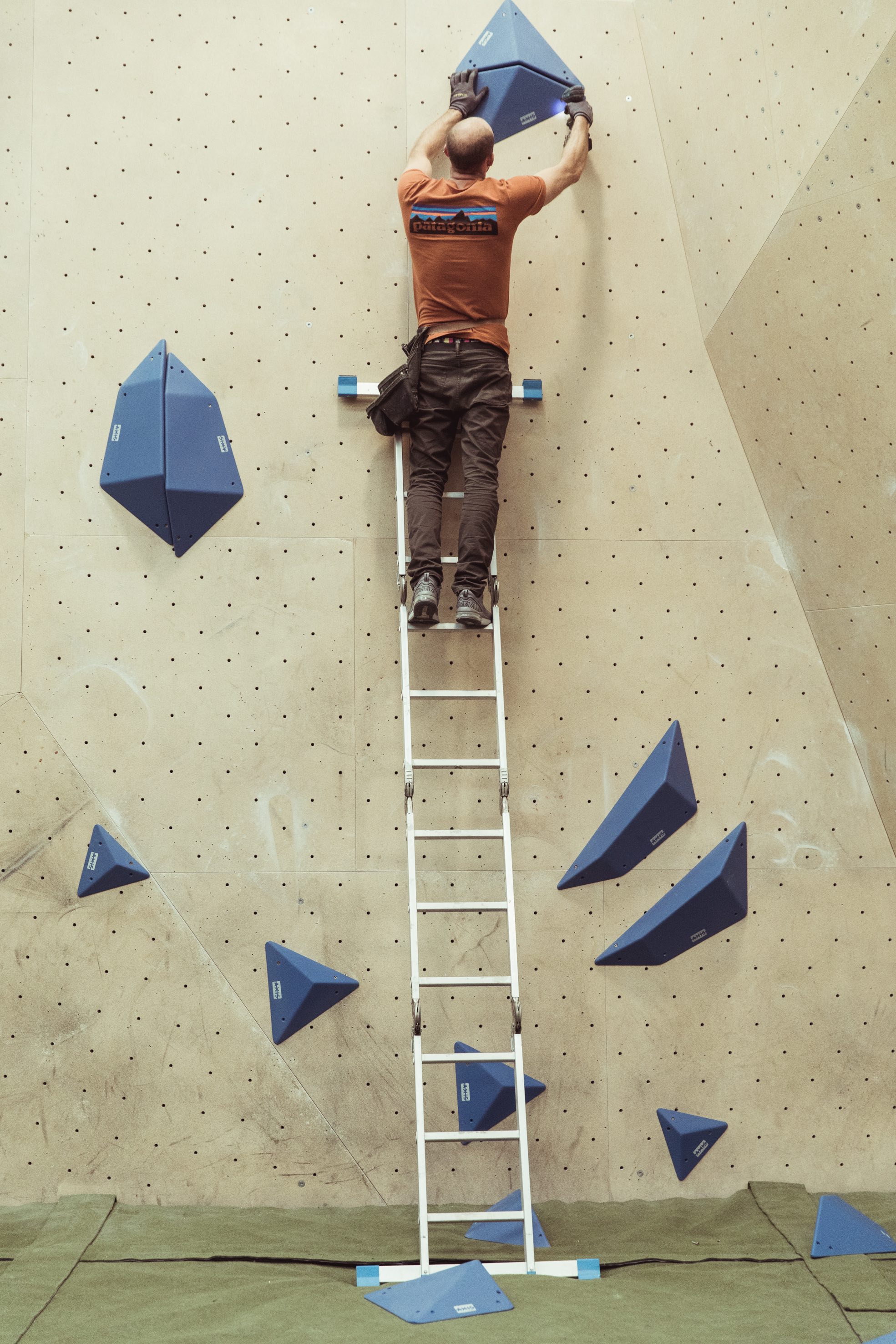 Route setter attaching final blue volume for competition final boulder. 